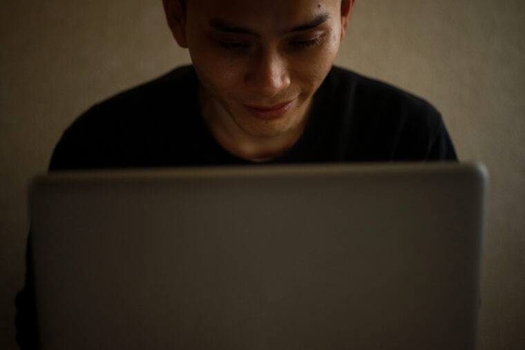 パソコンを見てニヤける男性の画像